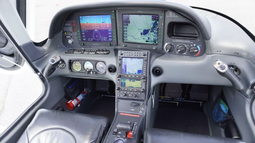 Cockpit of a small aircraft with dual glass cockpit displays, gauges, and control panels.