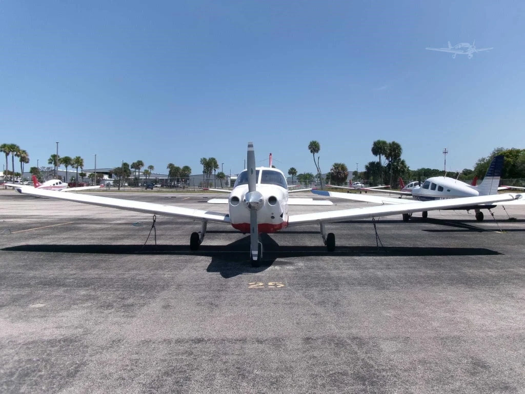 N4161Z front - Countrywide Flyers | Orlando Apopka X04 Front view of a small propeller airplane parked on the tarmac, with other light aircraft and palm trees in the background on a sunny day.